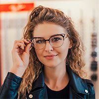View of a young attractive woman trying glasses at the optician.
