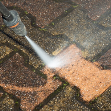 Pressure washer removing dirt from patio brick
