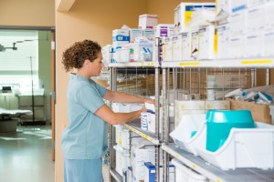 Side view of mid adult female nurse working in storage room of cancer hospital